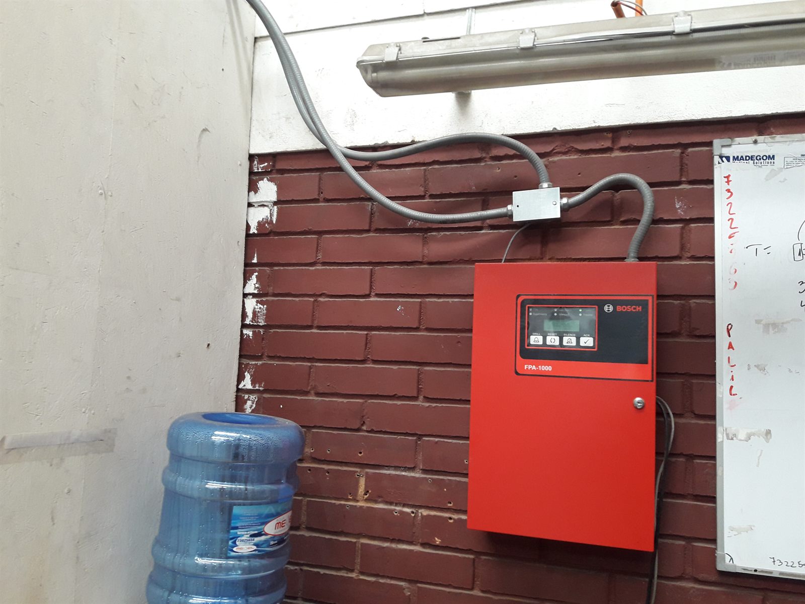 Panel de control de incendios Bosch FPA-1000 montado en muro con canalización rígida de cableado de la red de detección.