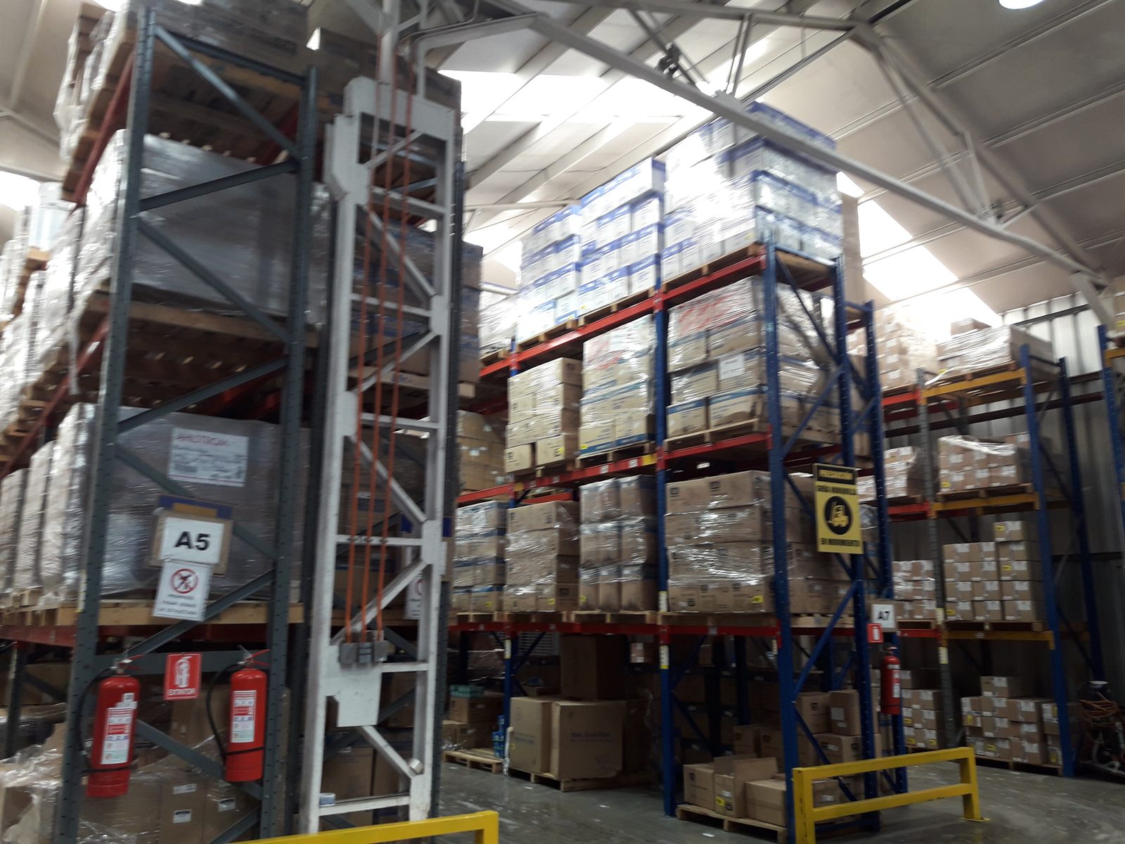 Extintores portátiles instalados y señalizados en racks de bodega, dispuestos según NCh 2095 / NFPA 10.